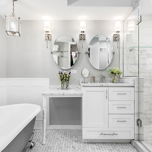 A bright small white bathroom featuring a freestanding bathtub oval mirrors elegant vanity and soft lighting to create a classic and clean design Castle Bathroom Tile Centre A bright small white bathroom featuring a freestanding bathtub oval mirrors elegant vanity and soft lighting to create a classic and clean design